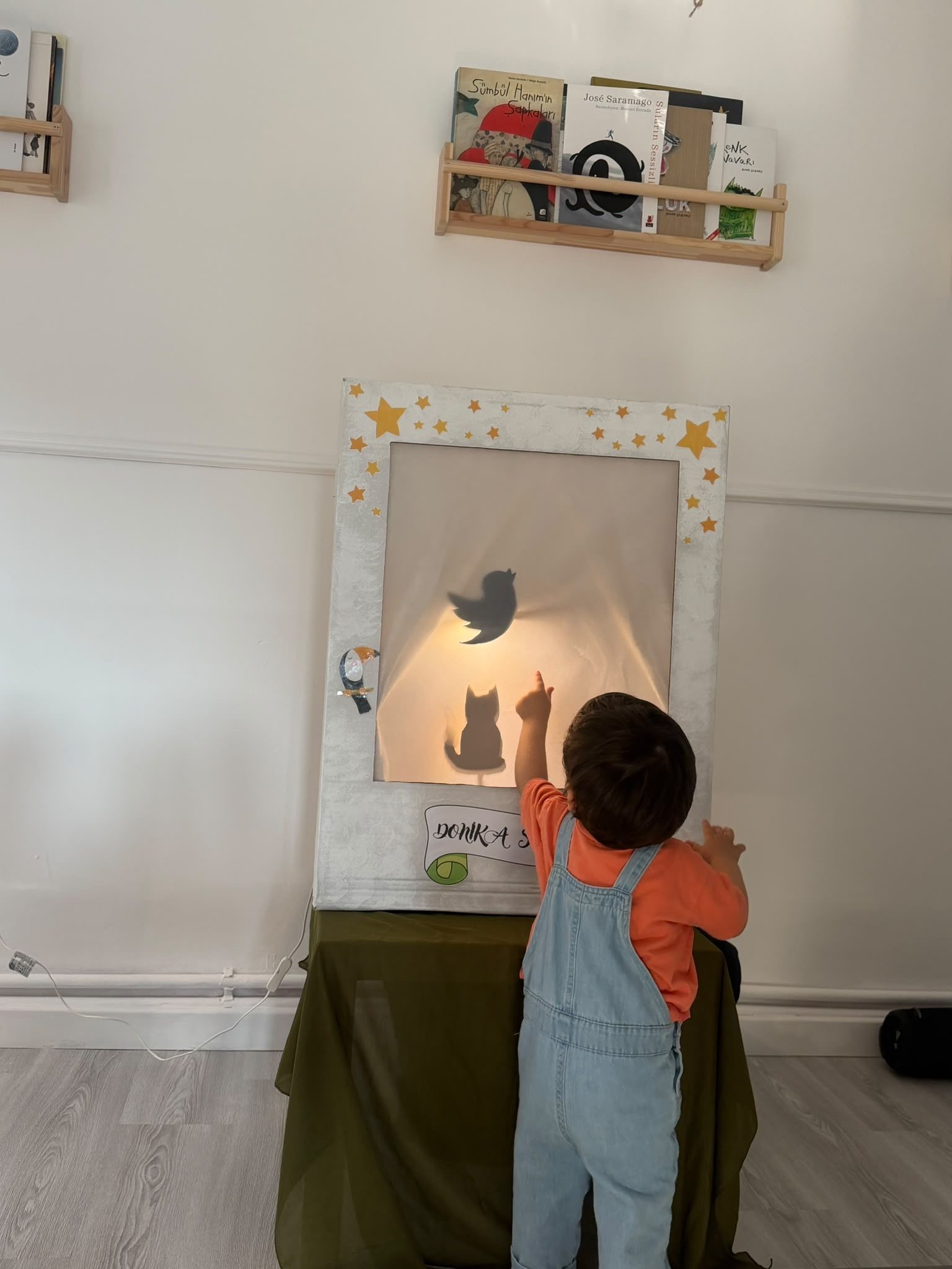 Işıklı perdede gölge oyunu oynayan çocuk